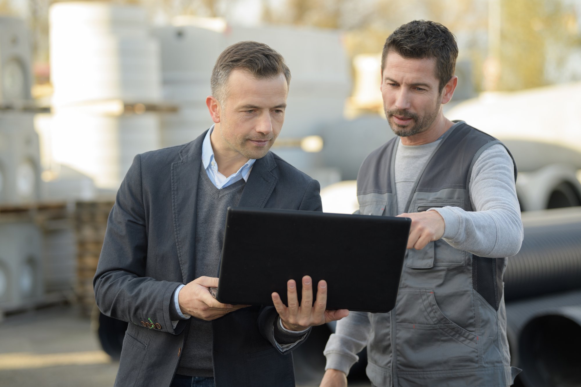constructor and manager working on modern tablet outside renovated factory